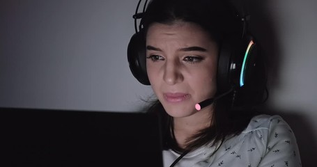 Woman gamer in bed. Caucasian woman on bed playing multiplayer game on laptop at night. Losing. Front shot with copy space.