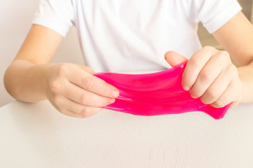 Modern toy called slime. Child playing transparent pink slime. Hands holding a mucus on a white background. Selective focus.