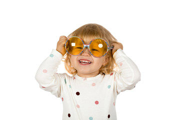 Portrait of a little blonde girl trying on big sunglasses