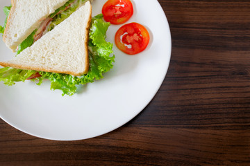 Sandwiches put on a white plate on a wooden table.