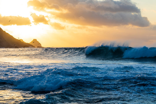 Waves crashing and birds flying in the background near sunset in Conceicao Beach in Fernando de Noronha, Brazil