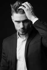 Fototapeta premium a young man in a suit. the man with the beard. Stylish Male portrait on a black background. black and white photo. male model. studio portrait. The guy in the classic suit