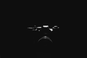 Old black film camera on black background under spot light.