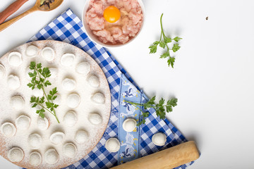 Obraz na płótnie Canvas Pelmeni, little dumplings lie on a cutting board, sprinkled with gray flour, top view.