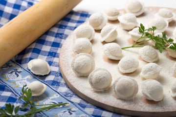 Fototapeta na wymiar Pelmeni, little dumplings lie on a cutting board, sprinkled with gray flour, top view.