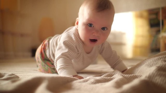 Infant baby boy learning to crawl in bed. Closeup on face. Slow motion, 4K UHD	