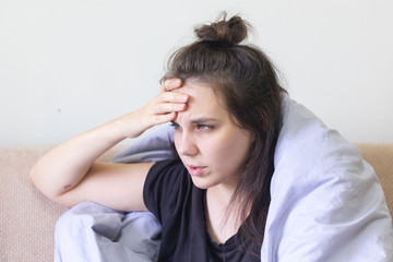 Sick young woman sitting at home with severe headache