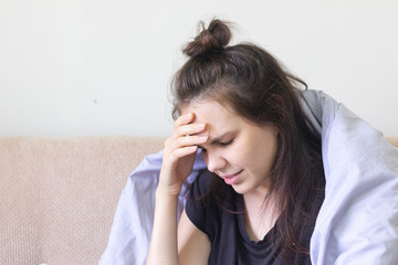 Sick young woman sitting at home with severe headache