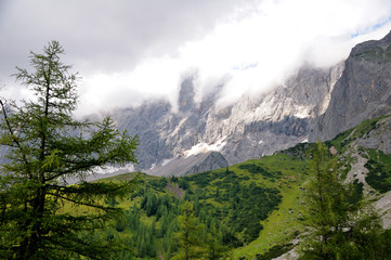 High mountain range, snow on the tops. White clouds cover the mountains.