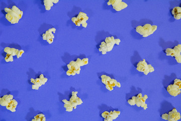 top view of popcorn in a pattern on purple indigo color background