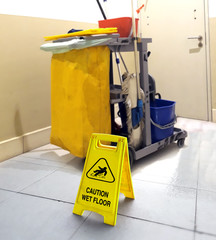 wet floor signage with cleaning tools in background