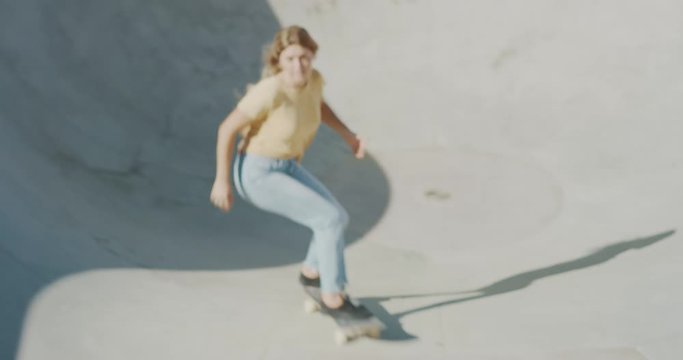 Vintage old school handheld shot of skateboarding in a pool bowl, skater girl carving in the pool bowl, extreme skating