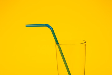 cocktail straw in the glass on yellow background