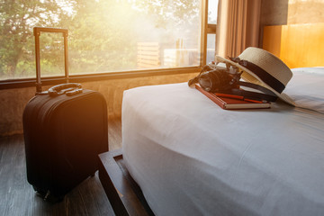 Travel accessories in comfortable hotel bedroom.