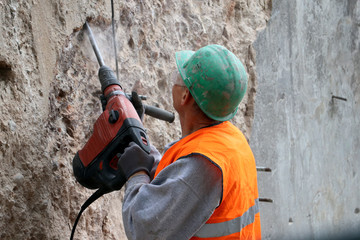 Builder worker with electric hammer drill  equipment on the  construction site