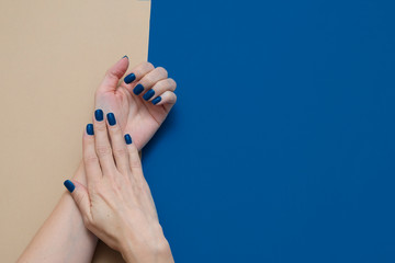 woman's hands with trendy blue nails on geometric blue and beige background