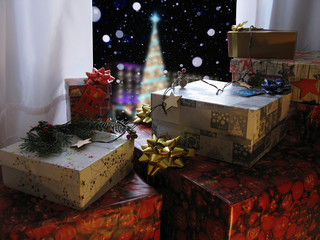 Christmas scene with gifts near window in room overlooking the Christmas tree.