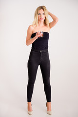 The concept of alcoholic relaxation. Full-length portrait of a pretty woman model with excellent make-up, beautiful hair on a white background standing with a glass of whiskey in her hands.