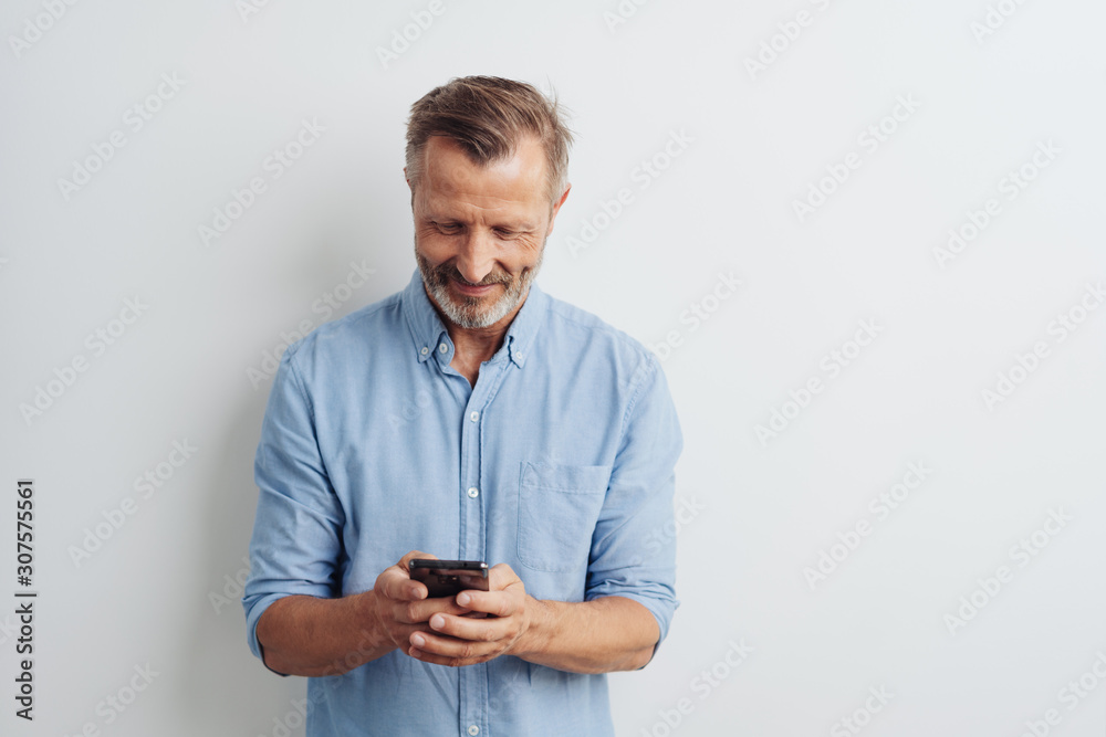Wall mural smiling middle-aged man texting a message