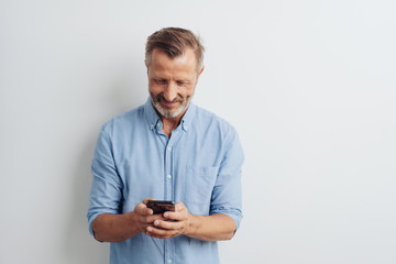 Smiling middle-aged man texting a message