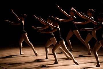 A choreographed dance of a group of graceful pretty young ballerinas practicing on stage in a classical ballet school