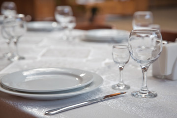 Tables set for meal . fork, knife . empty glasses and plates on the table in the restaurant .