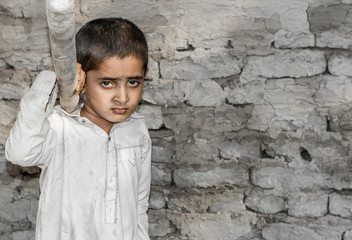 Obraz premium a very young orphan child is forced into child labor and working at a construction site and his expressions area full of pain 
