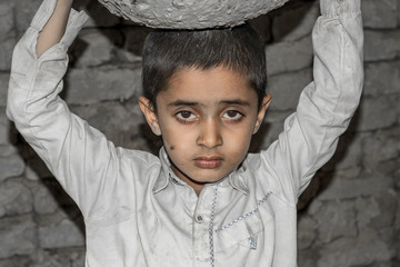 a very young orphan child is forced into child labor and working at a construction site and his...