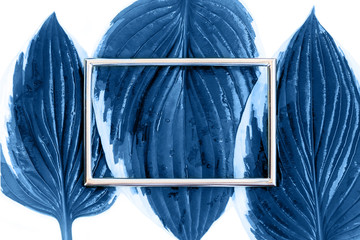 Creative blue layout made of tropical leaves with metal card note on the white background. Classic flat lay design. Nature concept