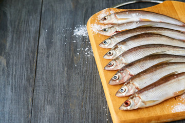 Raw vendace with salt on a wooden board