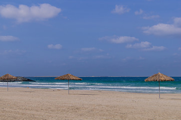 Sandy beach. Thatched umbrellas. Sea.