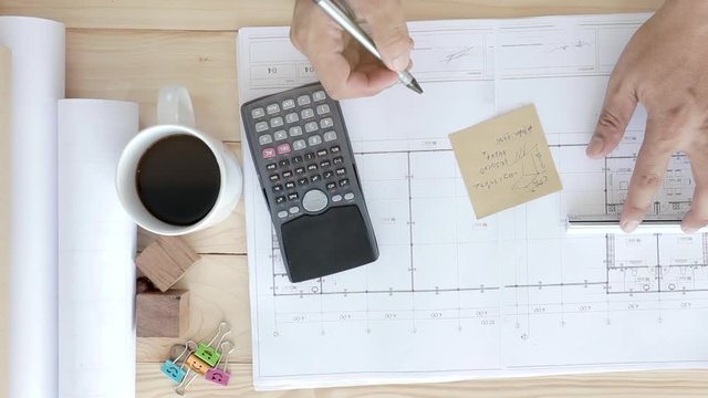 Engineers drawing home on the wood table, Architect design of house placed on wooden table, Male hands draw with a pencil and other drawing tools, Manipulator outline residence, Closeup slider view