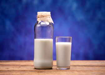 Milk in a glass bottle. Milk poured into a glass. Fresh milk in a bottle and a glass standing on a wooden table.