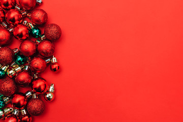 Red background with christmas balls on one side, space for text, flat lay.