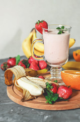 banana, strawberry and orange smoothies with mint on the table, front view - 307581554