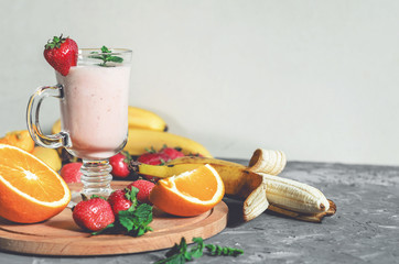 banana, strawberry and orange smoothies with mint on the table, front view - 307581583