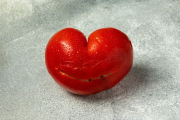 Ugly Organic Vegetable - Single red heart-shaped tomato on a gray background