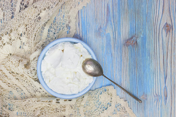 An overhead photo of fresh homemade cottage cheese in the teal blue ceramic bowl. Fermented product with Lactose. Organic eco healthy meal, dairy fresh milk products. Top view.
