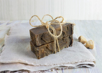 Fototapeta na wymiar Handmade lye soap bars, healing feminine concept. Eco organic lye soap with olive oil on the rustic wooden background. Spa natural body care accessories. Coal tar soap pieces.