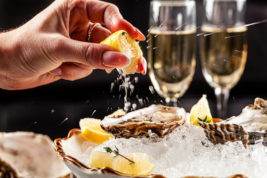 Prosecco bar concept. Open oysters lie on crushed ice with lemon and lime, next to a glass of champagne. Background image. Copy space.