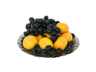 Oranges and grapes on a plate on a white background