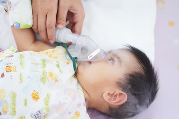 Close up of asian little baby boy is treated respiratory problem with vapor nebulizer to relief...