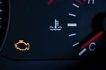Yellow lit engine error sign on car dashboard close up
