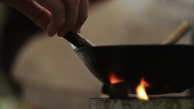 a closeup footage of indonesian batik canting on hot wax wok heated upon small stove, a traditional equipment for painting batik pattern