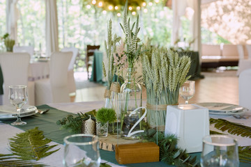 Beautiful floral arrangement in glass vase on wedding table in restaurant, copy space. Luxury wedding decorations. Table setting