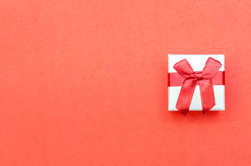 White box with red bow on red background. Concept of Valentine's Day, wedding, birthday, New Year, Christmas and other holidays