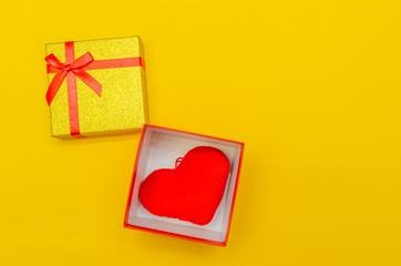 yellow shiny gift box with red heart inside on yellow background, top view, copy space. Greeting card for Valentine's day, holiday
