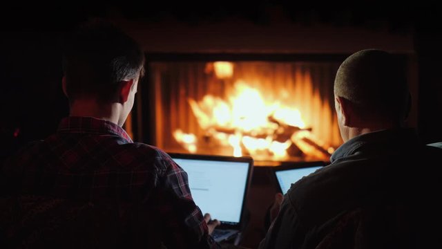 Winter evening by the fireplace - men use a laptop and tablet