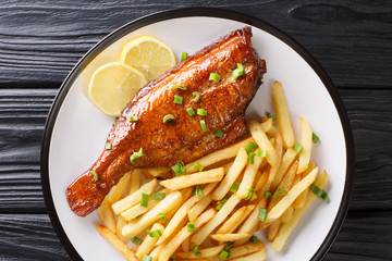 Baked sea perch fish with french fries and lemon juice close-up in a plate. horizontal top view