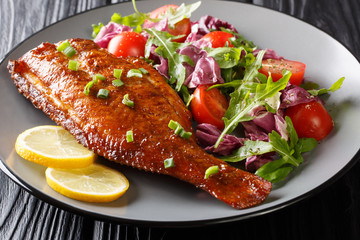 Whole spicy fried sea perch served with fresh vegetable salad close-up in a plate. horizontal